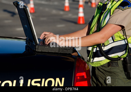 Une agente de police les types sur son ordinateur portable pendant un appel. Banque D'Images