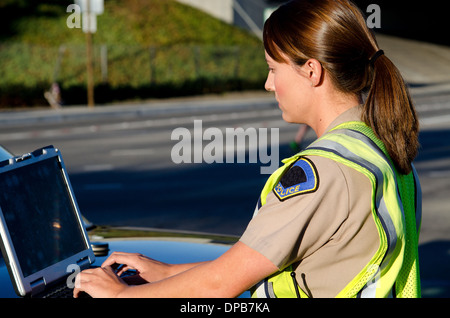 Une agente de police les types sur son ordinateur portable pendant un appel. Banque D'Images