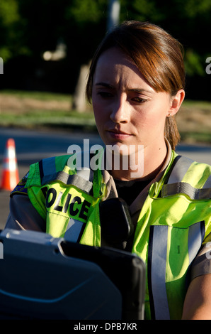 Une agente de police les types sur son ordinateur portable pendant un appel. Banque D'Images