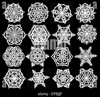 Ensemble de main fait découper des flocons blancs sur fond de papier noir Banque D'Images