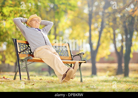 Représentant Senior assis sur un banc en bois et de détente dans un parc Banque D'Images