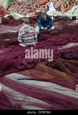 Les pêcheurs réparant ou la réparation des filets de pêche en nylon avec flotteur ligne dans le port de Fuengirola, Espagne. Banque D'Images