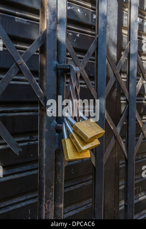 Plusieurs cadenas sécuriser une porte métallique coulissante du magasin à Sucre, Bolivie. Banque D'Images