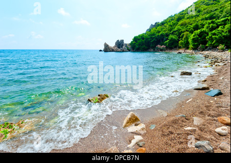 Plage rocheuse, colline verte, des eaux bleu azur de la mer. Banque D'Images