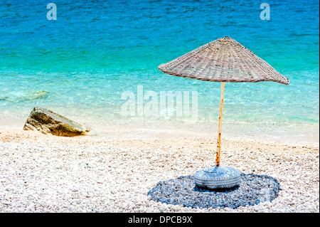 Wicker parasol sur la plage au bord de l'eau Banque D'Images