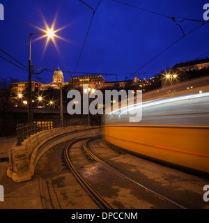 Des sentiers de lumière à partir d'un train qui passe à Budapest avec le Château de Buda en arrière-plan Banque D'Images