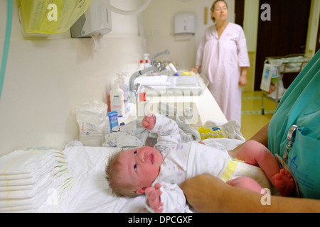 Robes des infirmières et infirmiers du nouveau-né un bébé dans une maternité pendant que la mère watches Banque D'Images