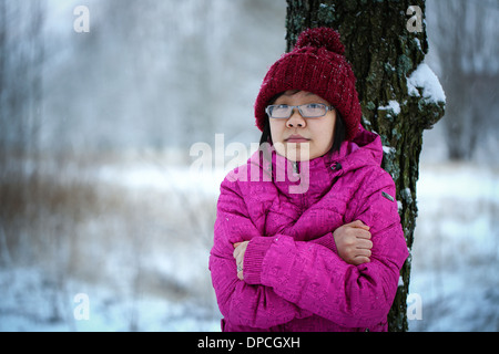 Jeune fille asiatique et d'humeur avec un dossier rose appuyé contre un arbre en hiver Banque D'Images