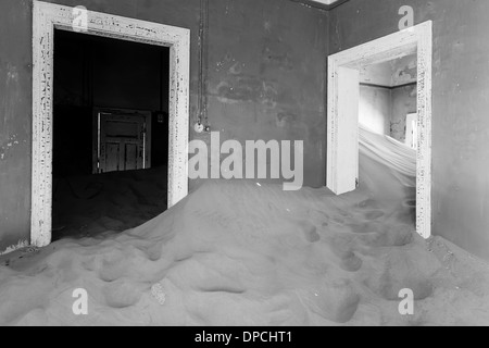Intérieur de maison remplie de sable en ville fantôme dans le désert de Namibie, autrefois une ville minière nommée kolmanskop noir et blanc Banque D'Images