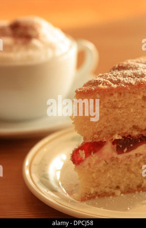 Café et gâteau cappuccino avec une tranche de confiture et de crème gâteau rempli Banque D'Images