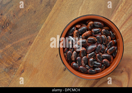 Haricots secs scarlet runner en brun plat sur une planche à découper rustique, avec place pour le texte Banque D'Images