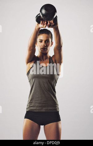 Jeune femme faisant de l'exercice avec un pivotement électrique bell. Femme de remise en forme Banque D'Images