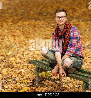 Les jeunes détendue hipster man reading book in nature, retour sur l'arbre, prairie derrière Banque D'Images