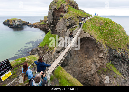Les visiteurs et les touristes à pied à travers le Carrick-a-rede Rope Bridge sur la côte d'Antrim en Irlande du Nord. Vue d'en haut Banque D'Images