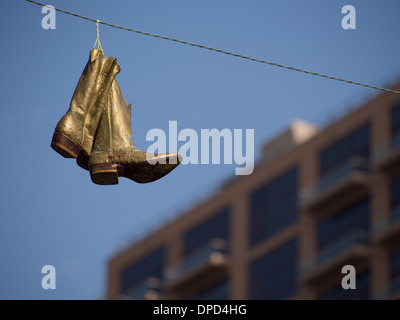 Bottes de cowboy d'or suspendu à une ligne électrique Banque D'Images