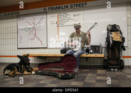 Un artiste de rue joue du banjo dans le métro accompagné de son chien Banque D'Images