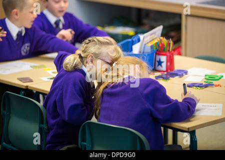 Deux amis chuchoter dans une classe de l'école primaire Banque D'Images