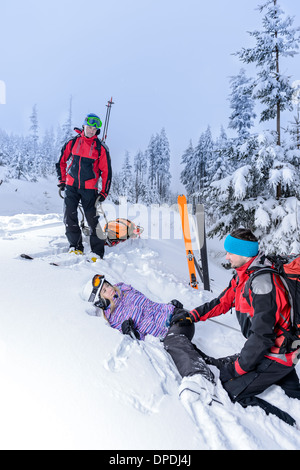 Aider patrouille de ski femme avec jambe cassée gisant dans la neige Banque D'Images