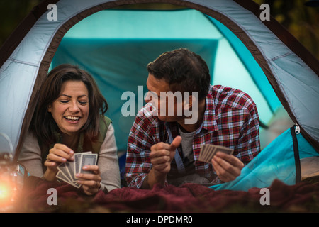 Mature couple lying together in tent, jeu de cartes à jouer Banque D'Images