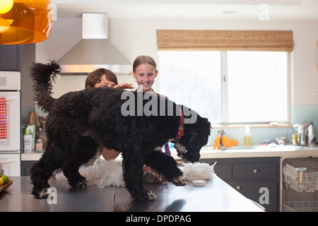 Mère et fille jouer avec chien sur compteur de cuisine Banque D'Images