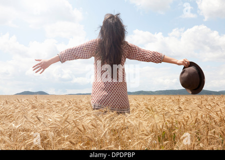 Mid adult woman standing in wheat field with arms out large Banque D'Images
