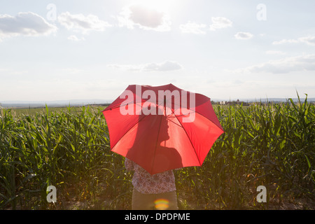 Femme debout tenant parapluie rouge Banque D'Images