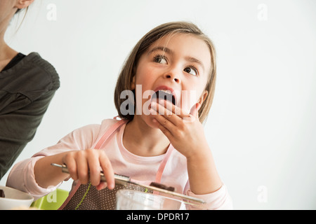 Girl licking batter de doigts Banque D'Images