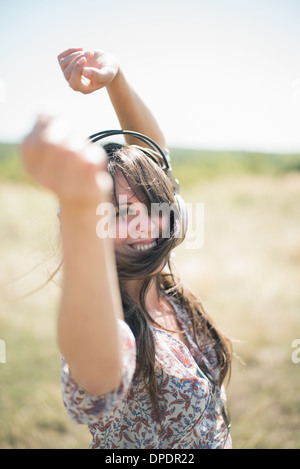 Portrait of mid adult woman dancing in field with arms raised, portant des écouteurs Banque D'Images