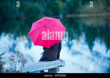 Femme avec un parapluie rose par le lac, Bellingham, Washington, USA Banque D'Images