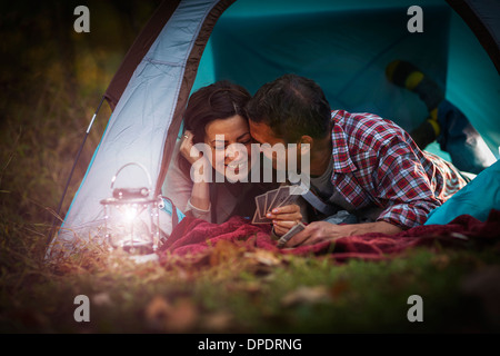 Mature couple lying together in tent, jeu de cartes à jouer Banque D'Images