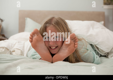 Portrait of Girl lying on bed in entre les pieds Banque D'Images