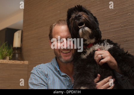 Portrait of young man holding up pet dog Banque D'Images