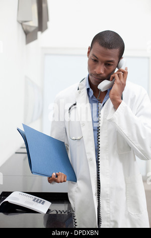 Médecin sur appel téléphonique, holding paperwork Banque D'Images