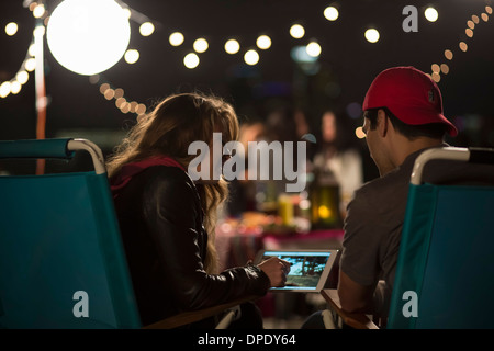 Young couple looking at digital tablet at rooftop barbecue Banque D'Images