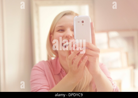 Young woman taking self portrait photograph using smartphone Banque D'Images