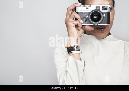 Studio portrait of young woman holding up camera Banque D'Images