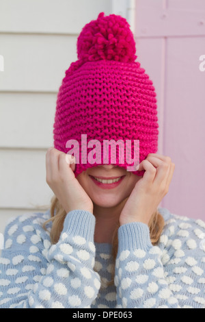 Portrait de jeune femme se cachant sous wooly hat Banque D'Images