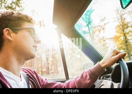 Young man leaning on country road driving convertible Banque D'Images