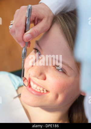 Dentiste à l'aide de miroir dentaire sur teenage girl Banque D'Images