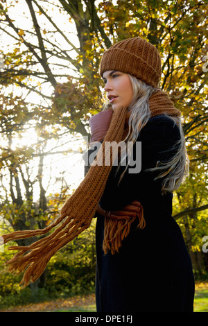 Jeune femme enveloppée dans autumnal park Banque D'Images