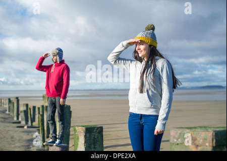 Jeune couple debout sur épis, Brean Sands, Somerset, Angleterre Banque D'Images