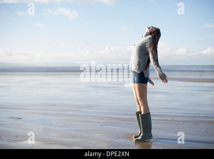 Young woman standing on beach looking up, Brean Sands, Somerset, Angleterre Banque D'Images