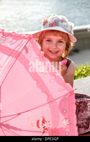 La jeune fille avec un parapluie est situé sur la rive du fleuve. Banque D'Images