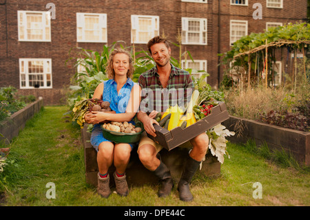 Couple holding récoltés légumes sur biens immobiliers du Conseil spécial Banque D'Images