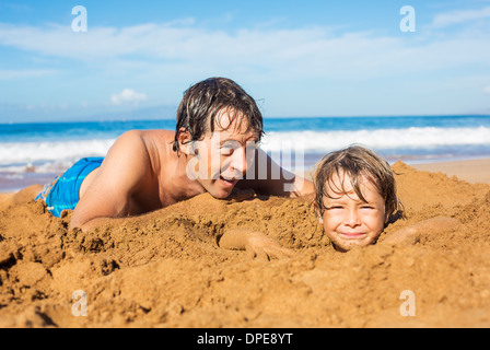 Père et fils jouent ensemble dans le sable on tropical beach Banque D'Images