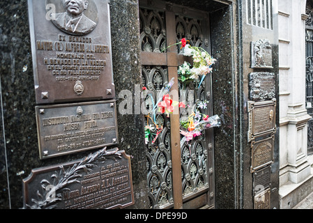 BUENOS AIRES, Argentine — des fleurs fraîches marquent le caveau de la famille Duarte dans le cimetière de Recoleta (Cementerio de la Recoleta), où repose Eva 'Evita' Perón. Le tombeau de l'ancienne première Dame d'Argentine, décédée en 1952, reste un lieu de pèlerinage pour les visiteurs et les fidèles. La modeste porte en bronze du mausolée Duarte contraste avec l’architecture ornée typique de ce cimetière historique. Banque D'Images