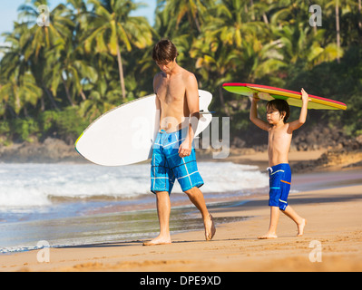 Père et fils aller surfer ensemble sur la plage tropicale à Hawaï Banque D'Images