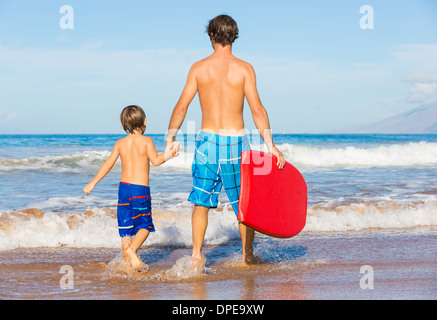 Père et fils aller surfer ensemble sur la plage tropicale à Hawaï Banque D'Images