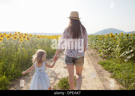 Mère et fille marche à travers champ de tournesols Banque D'Images