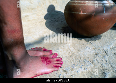 Jeune fille s'appuie contre un mur sur un chantier à Delhi. Ses pieds sont peint décorative avec rose rouge au henné. Banque D'Images